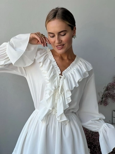 Detail of V-neck white chiffon dress featuring layered ruffles and drawstring closure