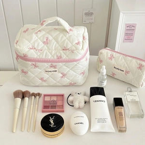 Close-up of quilted cotton cosmetic bag set with pink bow pattern and brand label
