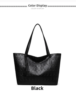 Close-up of black tote bag featuring embossed skull patterns and stylish fringe tassel