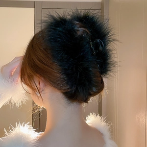 Detailed view of a black feather hair claw clip on an elegant updo hairstyle
