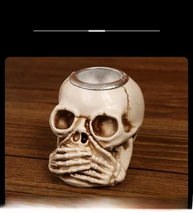 Close-up of antique ivory resin skull ornament with hands covering mouth on wood