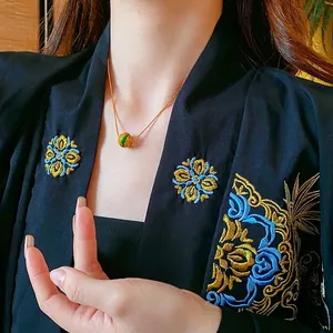 Collana tonda cava placcata oro 18 carati con motivi smaltati vintage su una modella