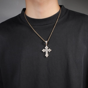 Détail d'un collier chaîne torsadée dorée avec pendentif croix serti de strass sur un mannequin