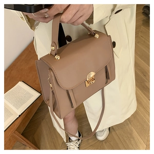 Close-up of a khaki matte leather flap square bag with a golden metal lock detail