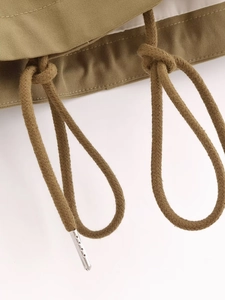 Dettaglio del cordoncino in cotone kaki con punte in metallo sulla giacca moda