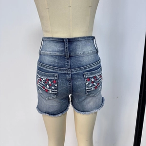 Détail du short en jean avec étoiles brodées rouges et blanches sur les poches arrière