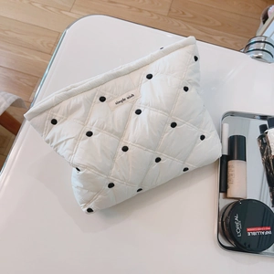 Quilted white cosmetic bag with black dots and simple wish label on white table