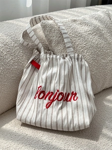 Striped canvas tote bag with red bonjour embroidery and drawstring closure in warm setting