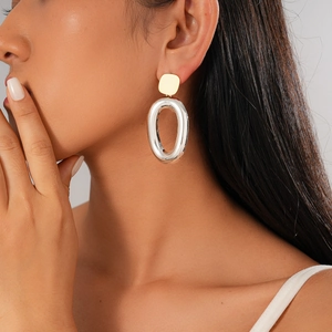 Close-up of minimalist gold square and silver oval geometric earrings on a model