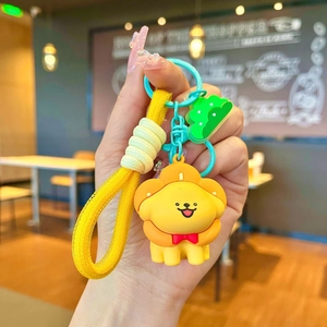 Detail of yellow lion cartoon keychain with green tree charm and braided wristlet strap