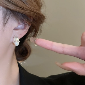Orecchini a fiore in argento con perle a goccia bianche indossati da una modella