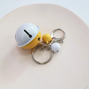 Close-up of yellow cartoon bell keychain with star cutout and metal braided rope