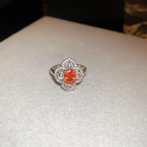 Detailed close-up of a silver ring featuring a large oval orange gemstone and halo diamonds