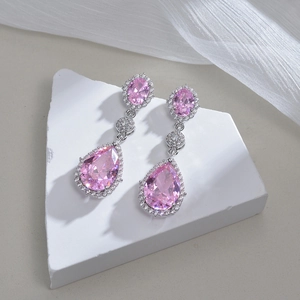 Pink pear-cut zircon drop earrings in stainless steel on white stone display