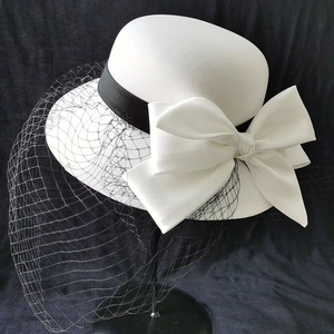 Elegant white vintage bridal pillbox hat with large satin bow and black mesh veil for women