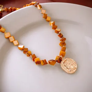 Vintage necklace with amber-tone square beads and embossed gold portrait pendant