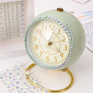 Close-up of a light green alarm clock decorated with colorful rhinestones and gold stand