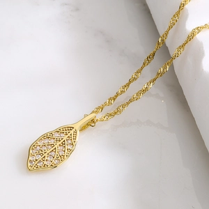 Elegant 18K gold plated leaf pendant necklace with zircon crystals on marble surface