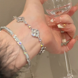 Macro view of silver-toned tennis bracelet and clover charm bracelet with zircons