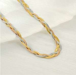 Macro detail of three-tone braided herringbone necklace in gold, rose gold and silver