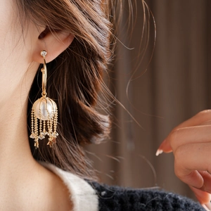 Détail de boucles d'oreilles dorées à franges avec perles et étoiles sur un mannequin