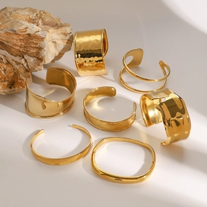 Minimalist gold stainless steel bracelets collection on natural rock with sleek metal finish