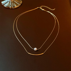 Detail of baroque pearl and gold bar double layer necklace on a dark textured background
