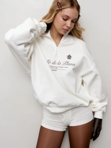 Detail of white American retro half-zip sweatshirt with chest logo and loose fit texture