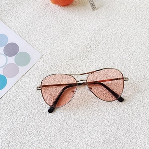 Detail of silver aviator sunglasses for kids with pink lenses on a textured white surface