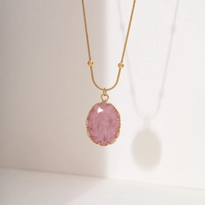 Elegant gold necklace featuring a large oval pink stone pendant on a white background