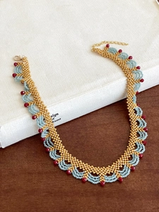 Détail du collier en dentelle de perles bleues et rouges avec fermoir doré poli