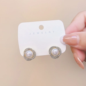 Detail showing elegant pearl earrings with sparkling diamond accents on a jewelry card