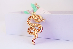 Close-up of golden snake keychain with hollow heart patterns on white gift box