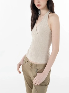 Detail of beige ribbed knit texture on a crisscross halter top with slim fit design