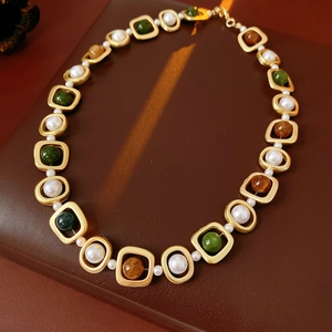 Détail du collier vintage avec perles et pierres vertes sur fond en cuir marron