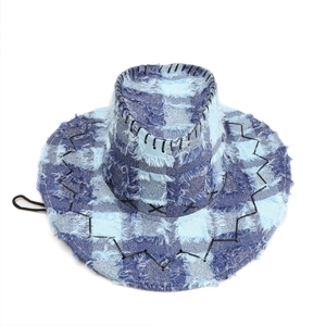 Macro detail of raw fringe edges and black wavy stitching on blue plaid denim cowboy hat