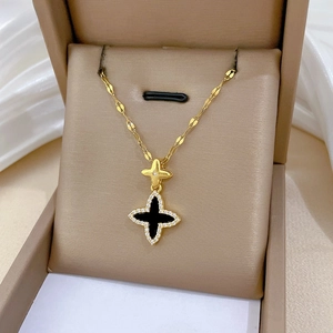 Macro detail of gold titanium clover necklace with black inlay and crystal embellishments