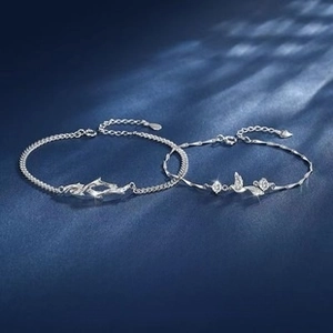 Close-up of silver thorn and bird couple bracelets on elegant blue silk background