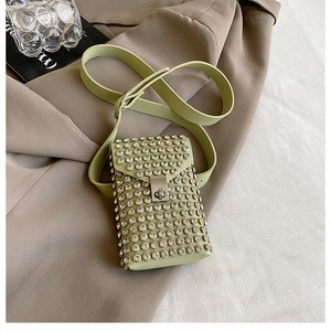 Close-up of green mini crossbody bag with round rhinestones and a metal lock buckle