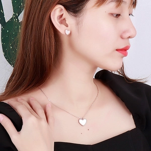 Detail eines Roségold-Schmucksets mit herzförmiger Kette und Ohrringen mit Muscheleinlage