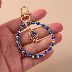 Detailed close-up of golden Hamsa hand keychain with blue evil eye beads and wrist strap