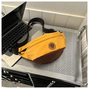 Detail of yellow and brown oxford cloth crossbody bag with adjustable strap on a rack