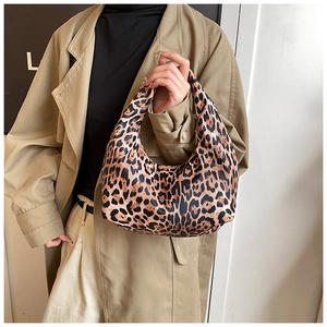 Détail d'un sac hobo à imprimé léopard porté par un mannequin en trench-coat élégant