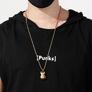 Macro shot of hip hop style gold fist pendant on a curb chain worn by a male model