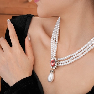 Détail d'un collier de perles multicouches avec gemme ovale rouge et perle pendante