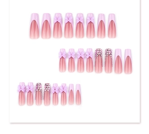 Detail of pink French press-on nails with purple bow accents and sparkling rhinestones