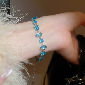 Detailed view of silver bracelet with geometric blue stones on woman's wrist