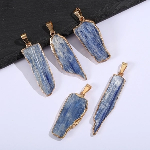 Five irregular natural blue kyanite pendants with gold edges on a stone and white background