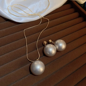 Élégant ensemble collier et boucles d'oreilles en perles dorées sur velours marron