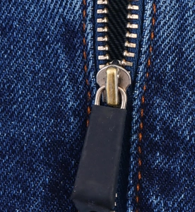 Dettaglio della cerniera in metallo dorato su giacca di jeans blu con cuciture arancioni a contrasto
